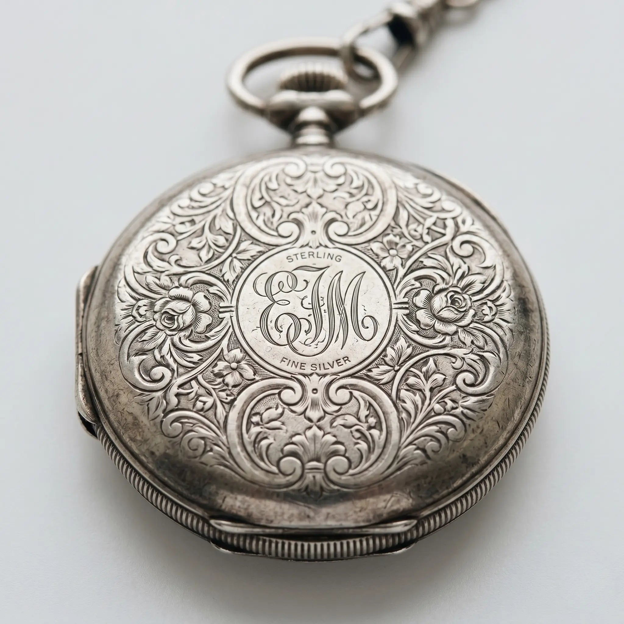 Sterling silver engraved pocket watch showcasing detailed floral case designs. Image