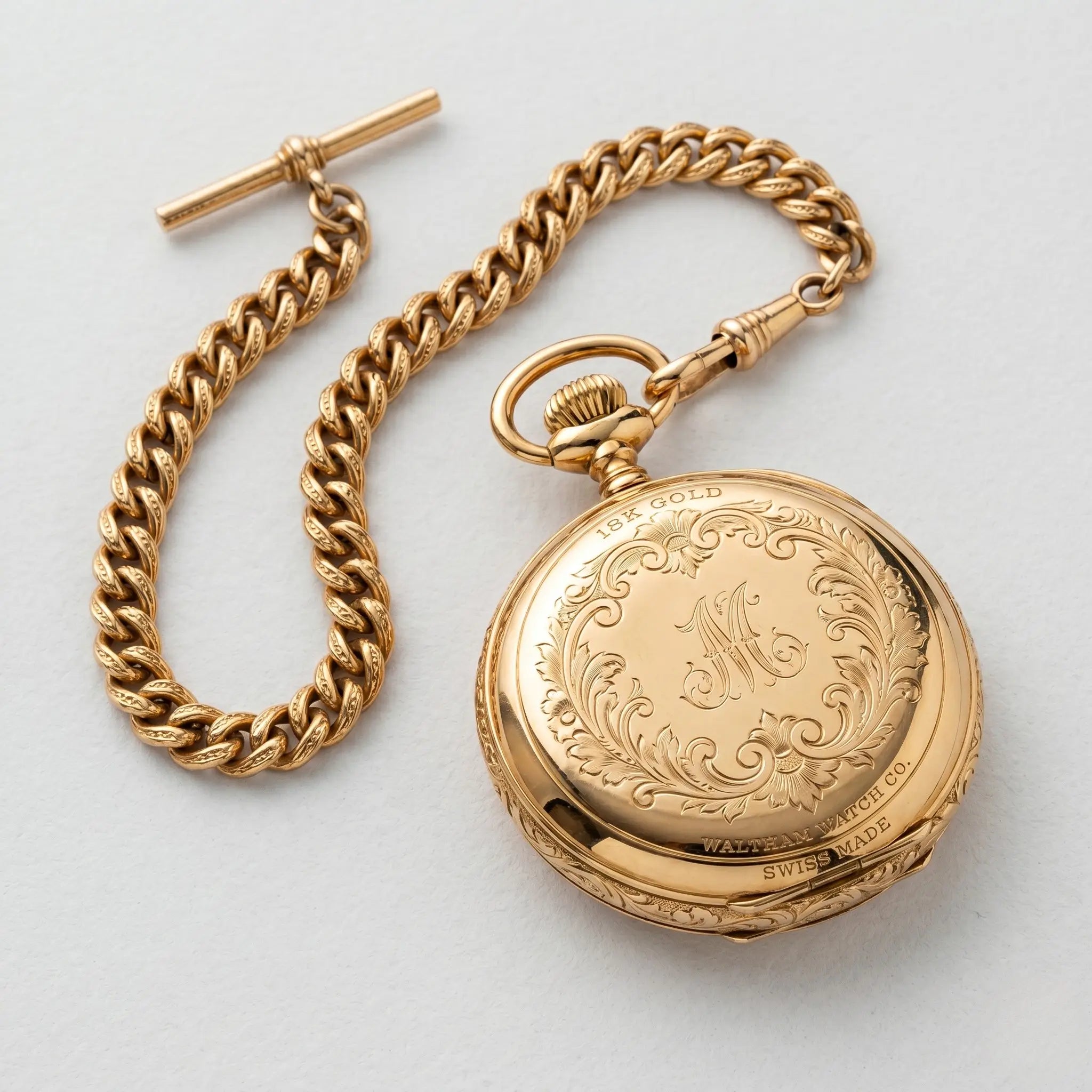 Luxurious 18k gold pocket watch and matching chain on a clean light background. Image