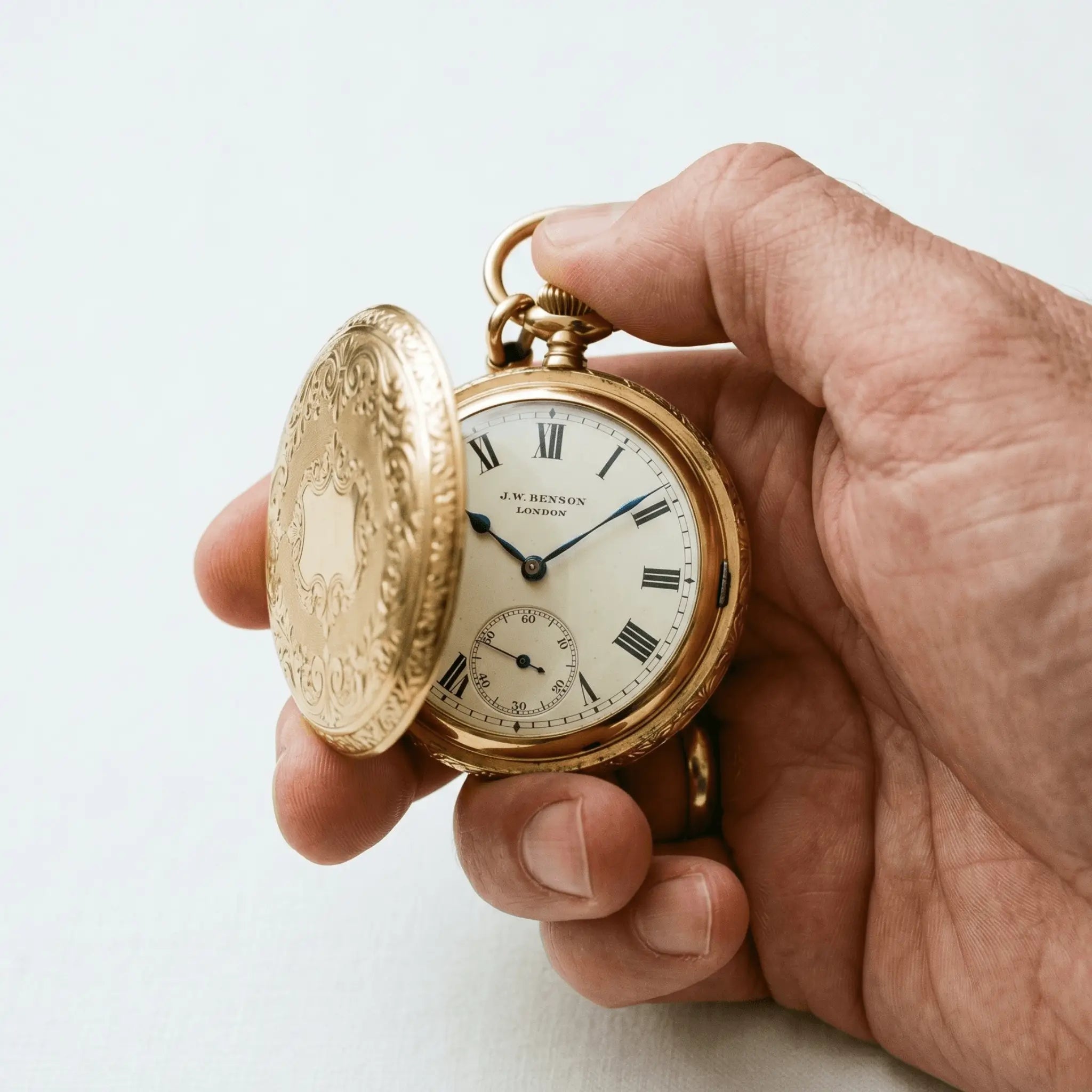 Polished gold hunter pocket watch with an open protective cover revealing the dial. Image