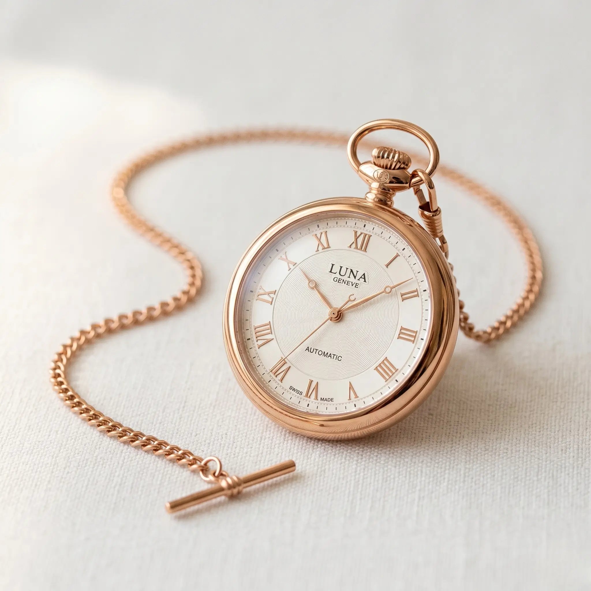 Elegant rose gold pocket watch and chain against a soft light grey background Image