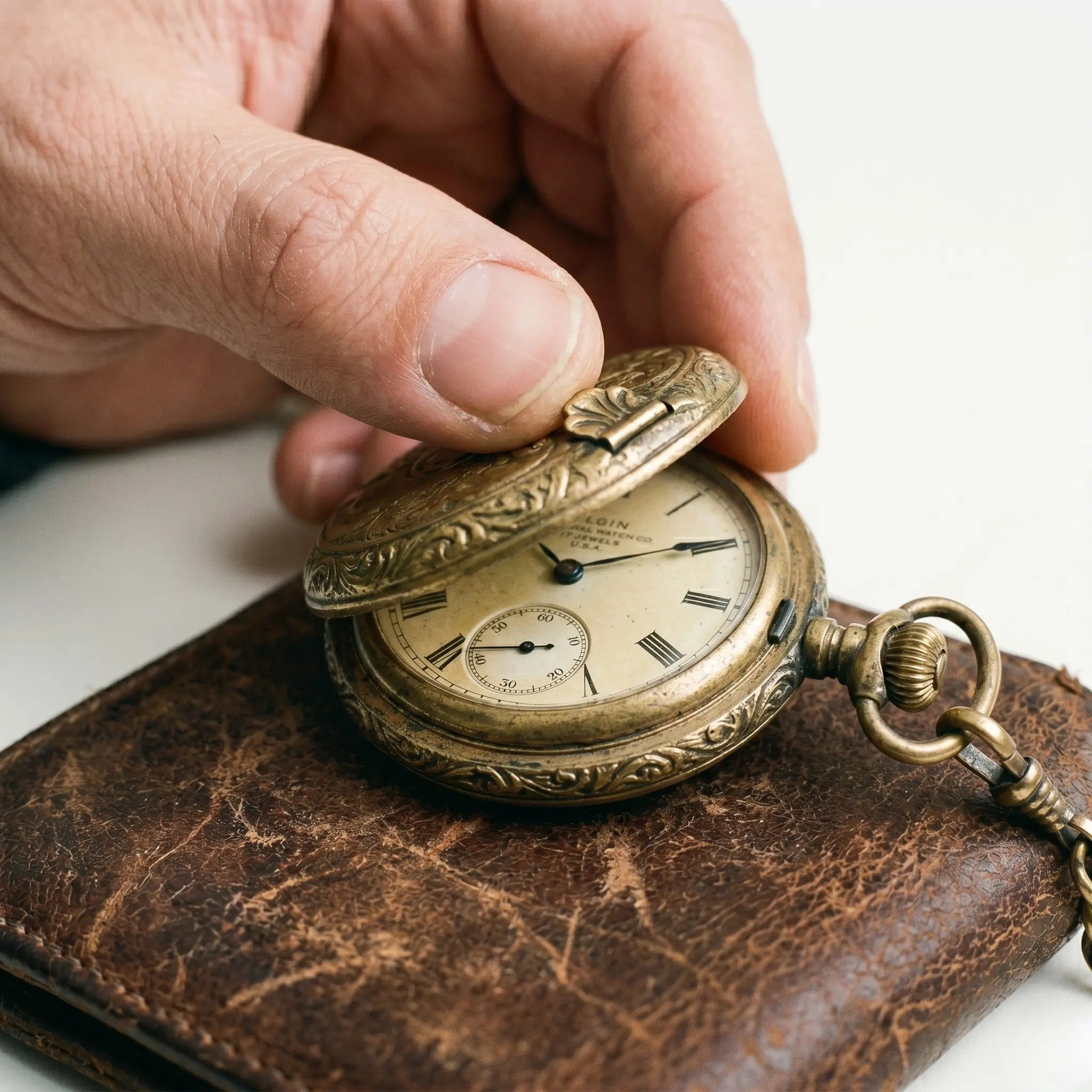 Antique brass vintage pocket watch with an open hinged cover on worn leather. Image