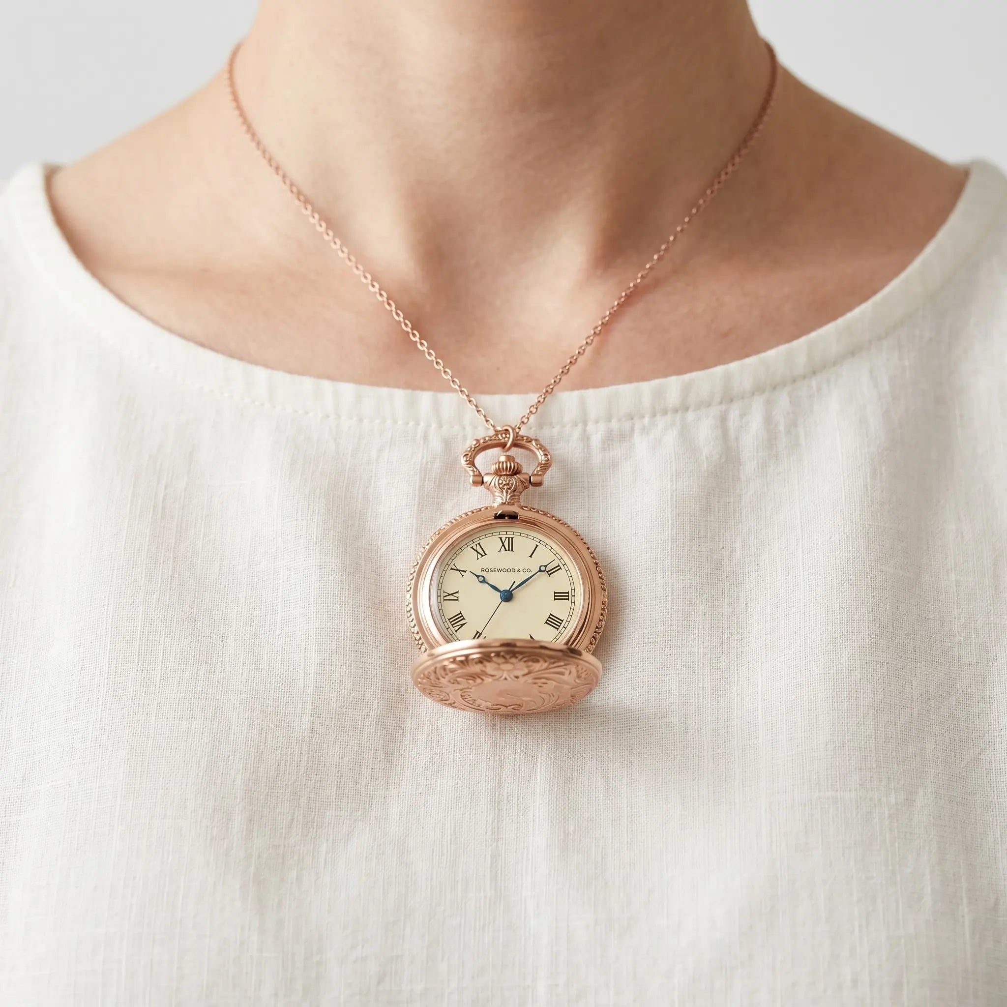 Ornate rose gold women's pocket watch worn as a delicate pendant necklace Image