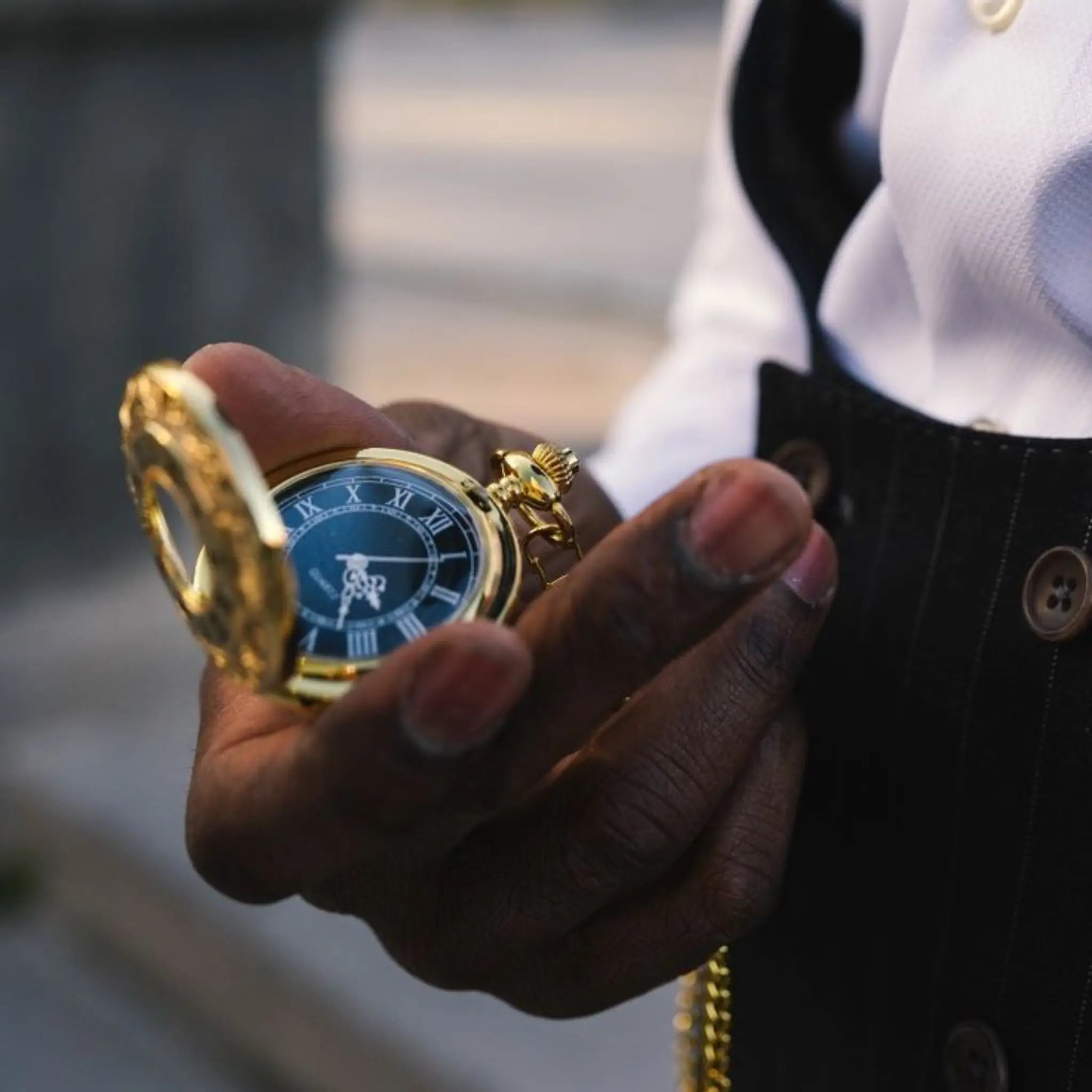 Hand holding a gold pocket watch with a blurred background Image