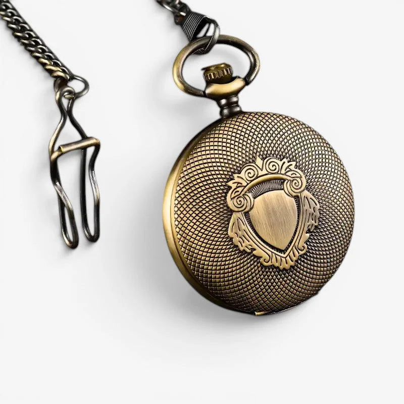 Antique brass-finished automatic pocket watch with textured grid pattern and ornate shield emblem on the front