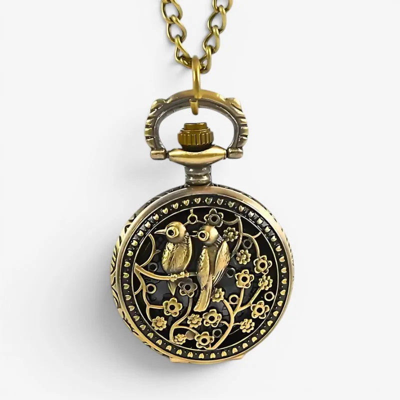 Antique-style brass bird necklace pocket watch with intricate floral filigree on black enamel suspended from chain