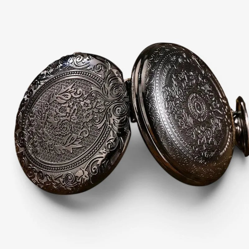 Black quartz pocket watch with antique-style black case featuring intricate floral and scrollwork engraving on both faces