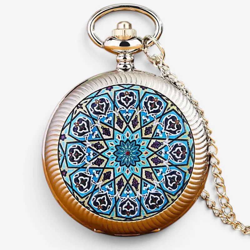 A silver and gold-toned blue flower pocket watch with an intricate blue black and white geometric pattern on its face