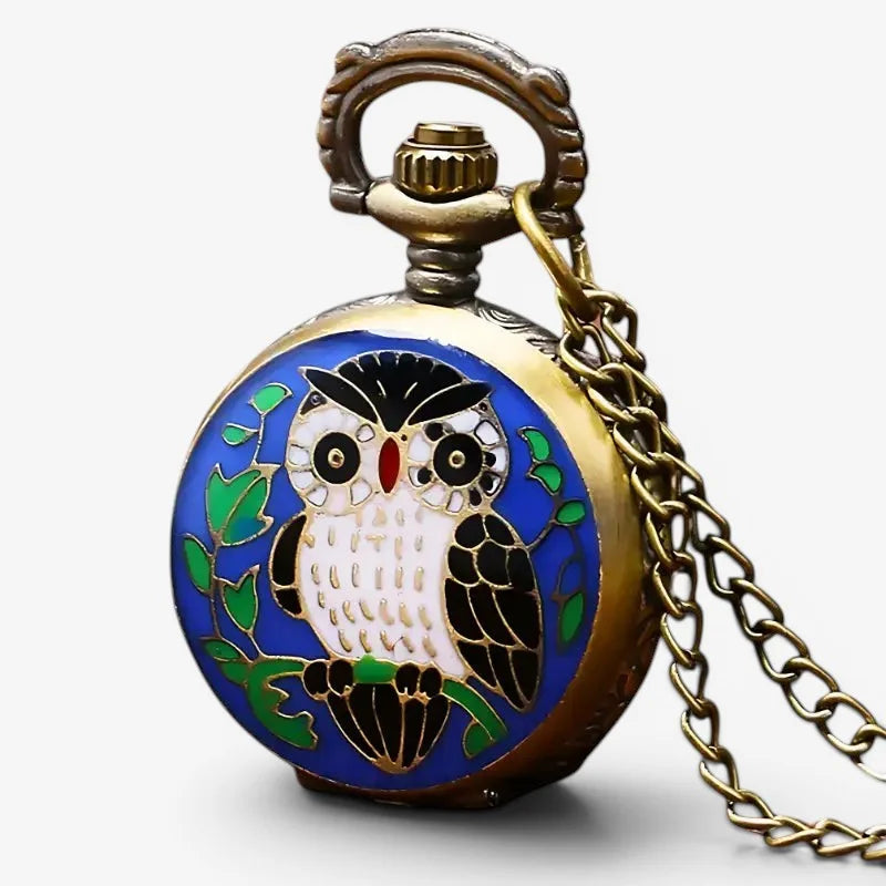 A vintage-style brass blue owl pocket watch with enamel design green leaves on a vibrant blue background