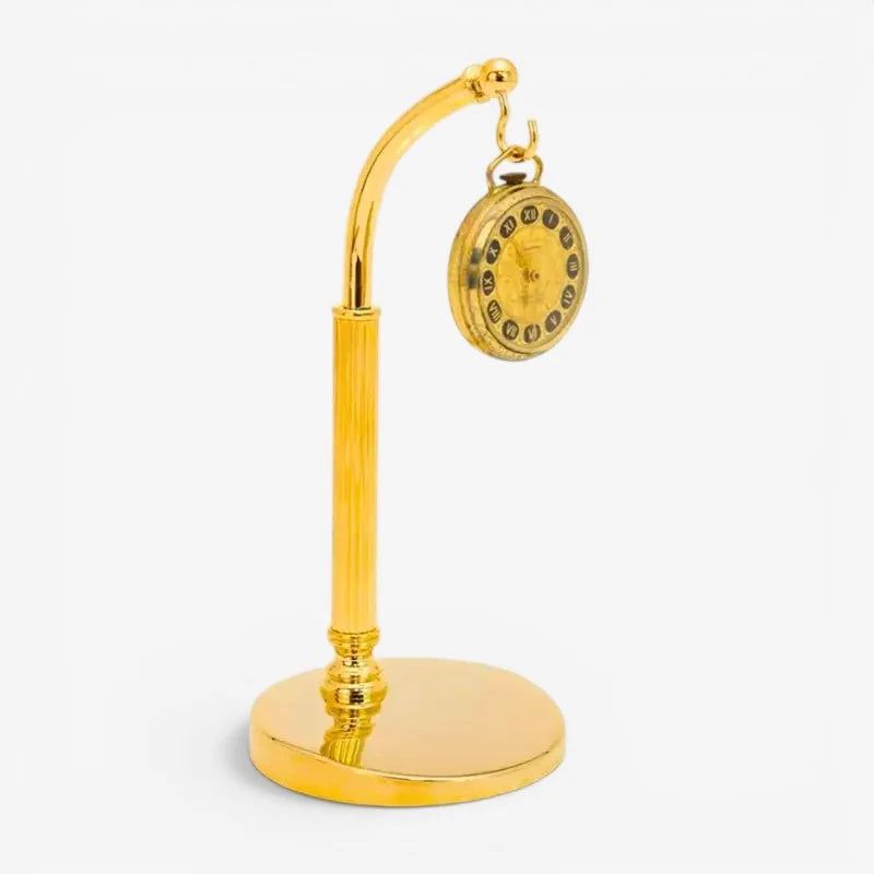 Golden pocket watch with roman numerals hanging from a matching gold-colored brass pocket watch stand
