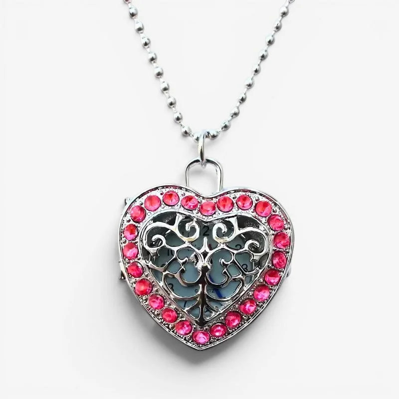 Silver heart watch necklace with red rhinestone border and intricate filigree design on the front side