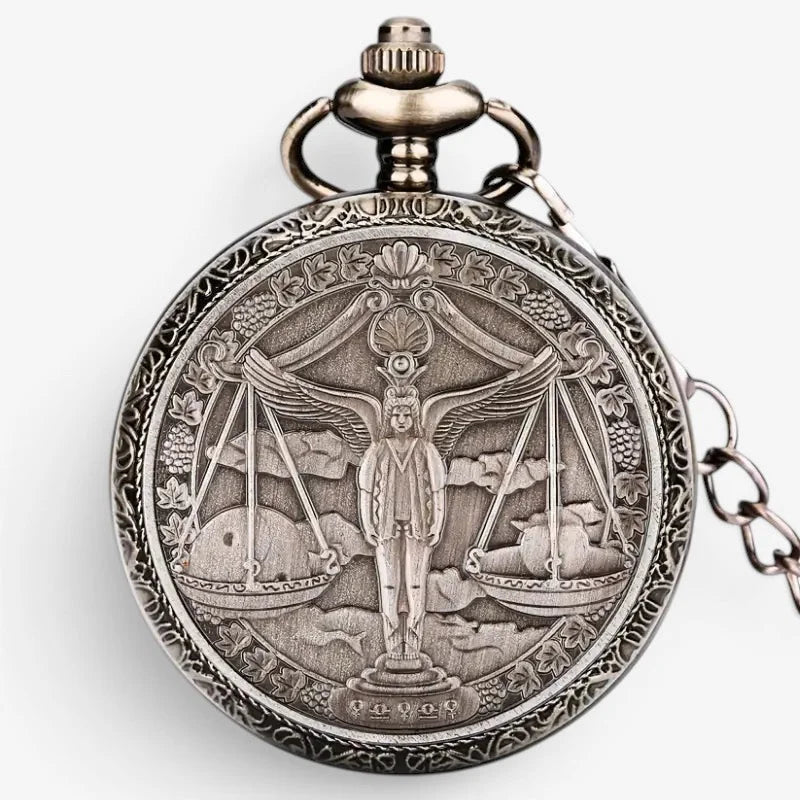 Antique silver-toned horoscope pocket watch with intricate engraved winged figure on scales surrounded by grapevines and leaves
