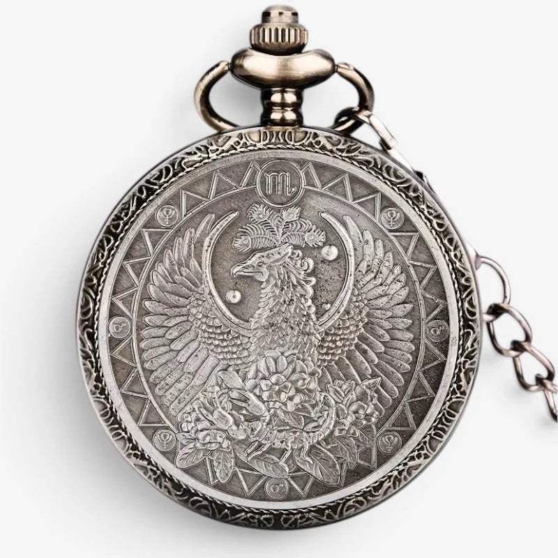 Antique silver-toned horoscope pocket watch with intricate engraved phoenix, floral motifs, and astrological symbols on back