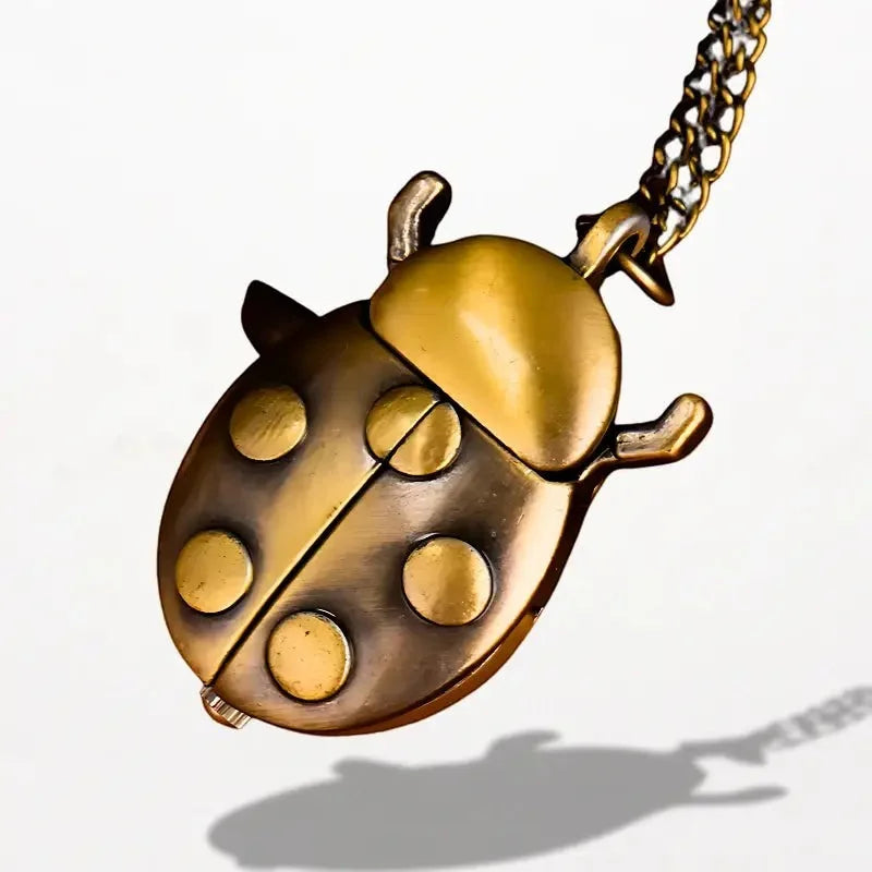 Golden brass ladybug nurse watch locket with six raised circular spots and chain attachment