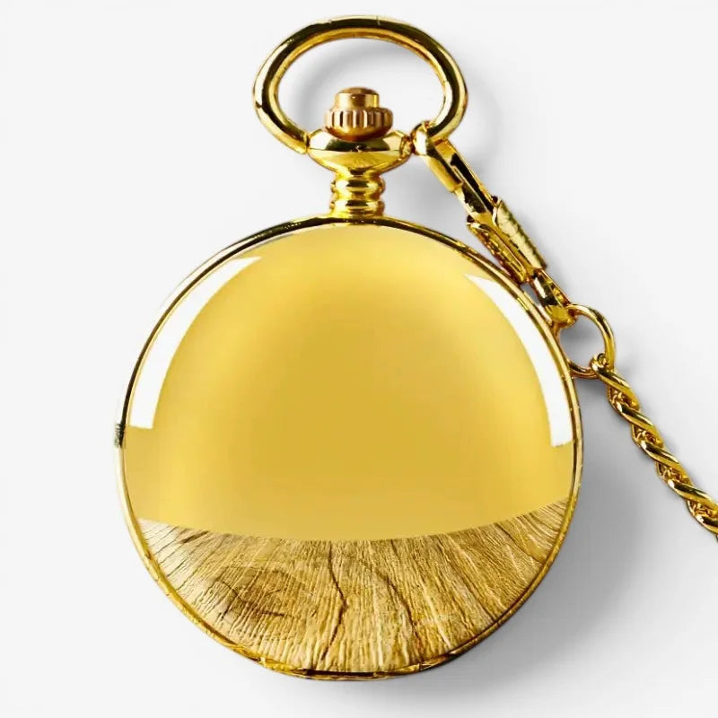 Old gold pocket watch with polished reflective surface and textured wood grain pattern on the bottom half