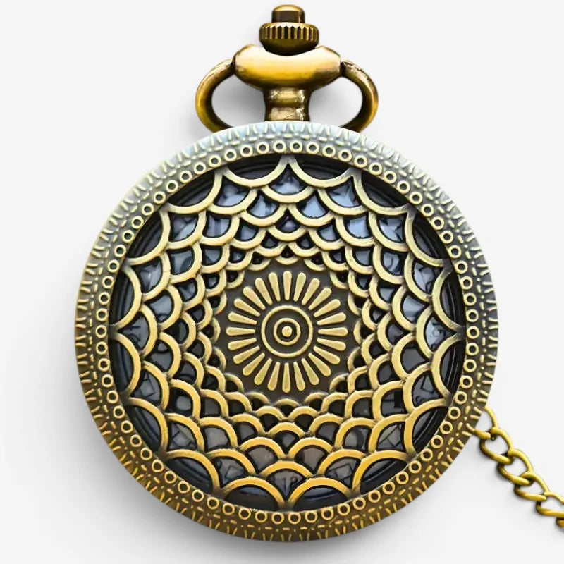 Antique-style brass pocket watch with intricate sunburst filigree and dark inlaid center attached to a chain