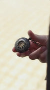 A man in a classic grey tweed blazer pulls a black men's steampunk steel pocket watch from his pocket by its chain, opening the front cover to reveal the exposed mechanical gold gears inside