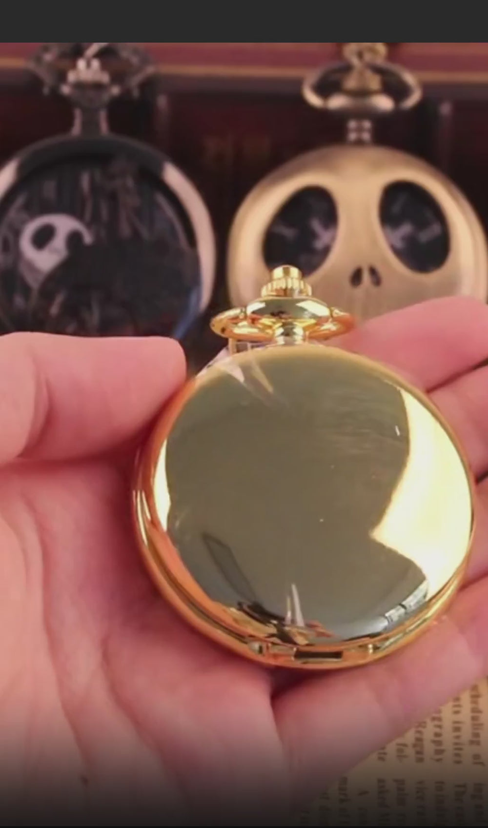 A close-up of a classic men's gold mechanical pocket watch being held by its vintage chain, with the front cover opening to reveal the intricate moving gears inside.