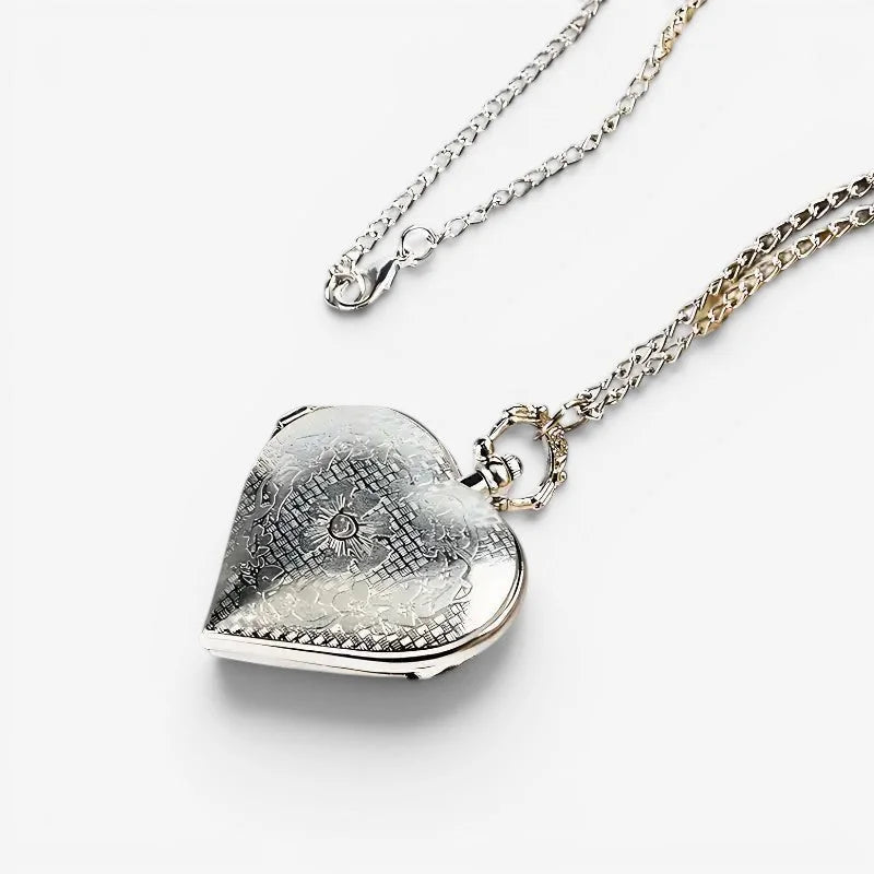 Silver heart pocket watch locket with intricate engraved floral and geometric patterns on a delicate chain