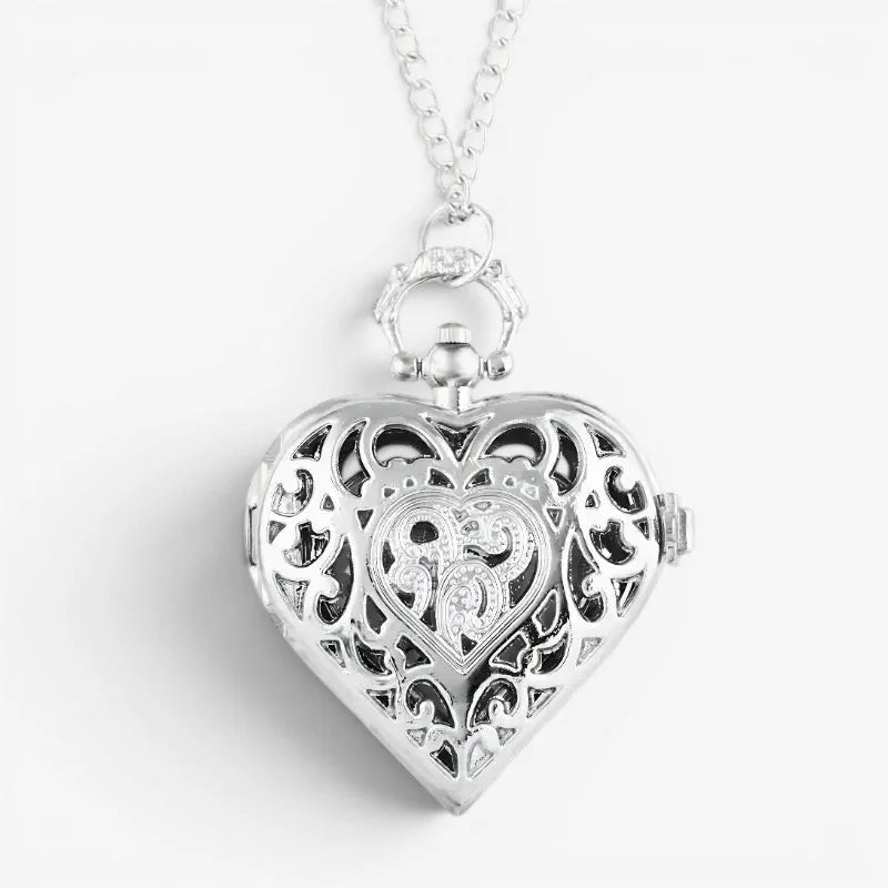 Silver heart pocket watch with intricate filigree design and central engraved monogram on the front side