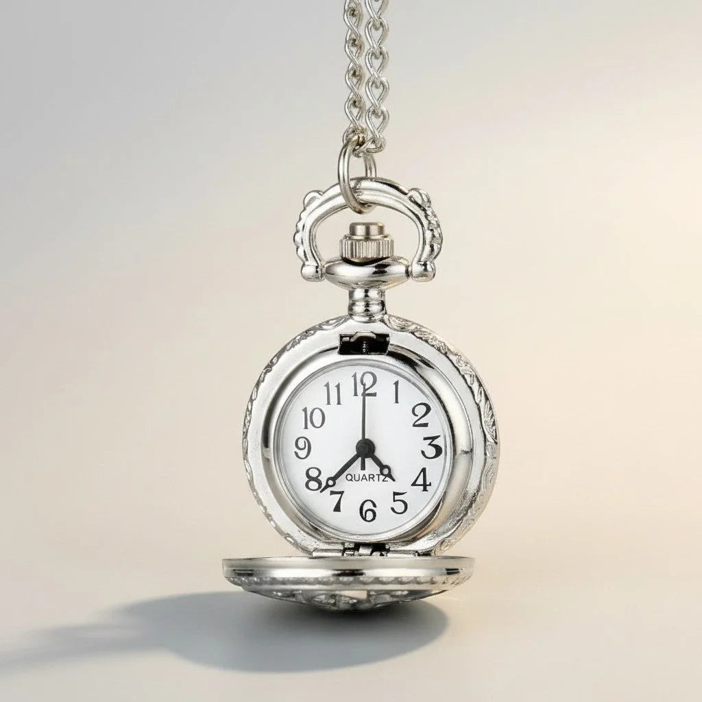Small antique silver pocket watch with ornate case and white face featuring black numerals and a chain