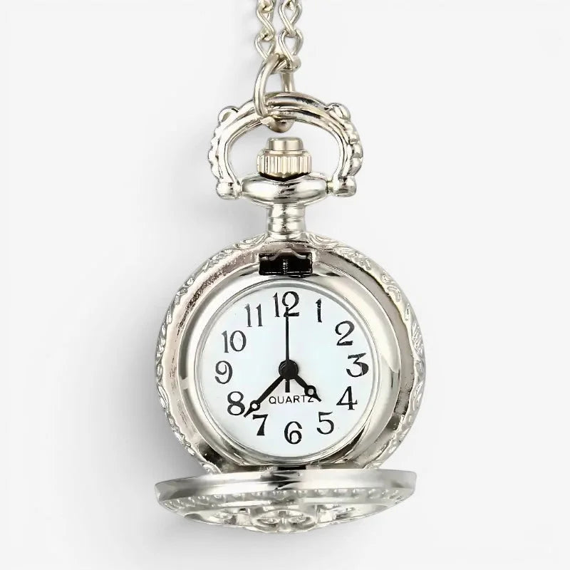 Small antique silver-toned pocket watch with ornate engraved case and white dial with black arabic numerals