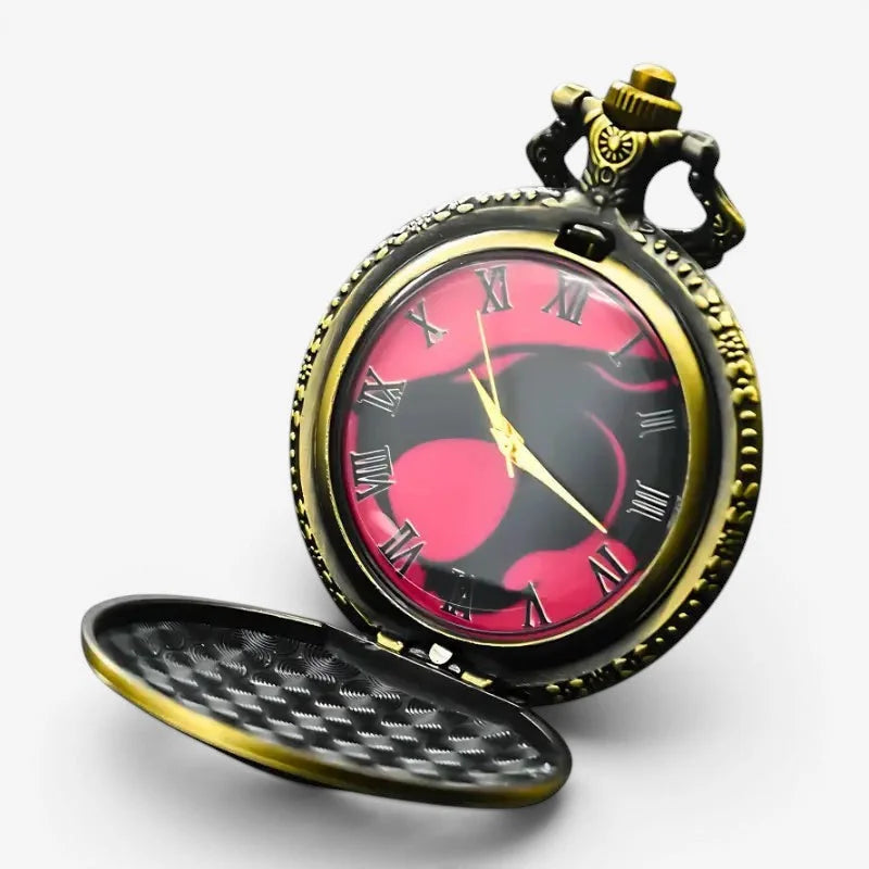 A vintage style thundercats pocket watch with a black and pink heart patterned face and ornate gold toned casing