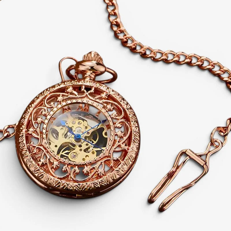 Womens rose gold mechanical pocket watch with ornate design, visible gears, blue hands, and matching chain